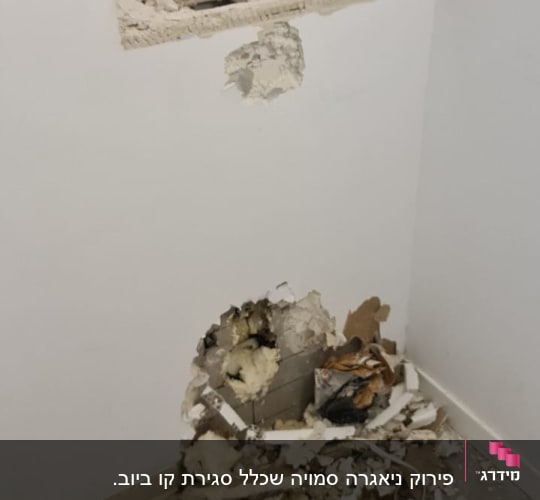קיר עם חור ושברי טיח על הרצפה